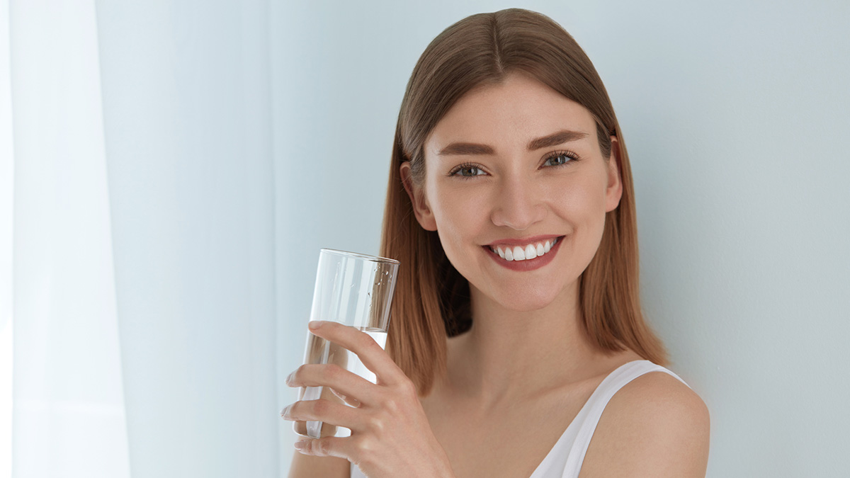 donna sorridente con bicchiere d'acqua