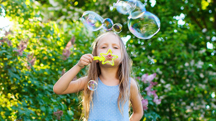 bambina che soffia bolle di sapone